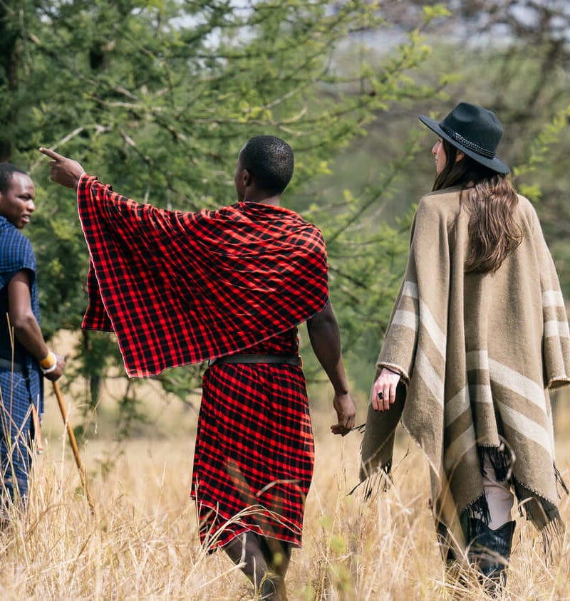 A tourist takes a Tanzania safari with a Maasai guide on the savannas of the Serengeti