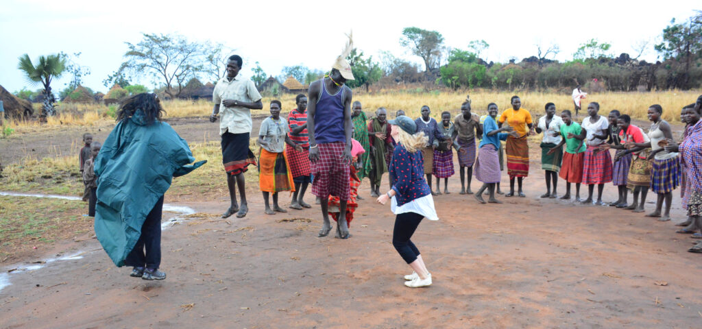 Guests dance with locals in a Karimojong homestead in north eastern Uganda - Nandi Adventures